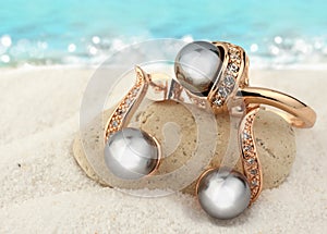 Jewelry set with black pearls on sand beach background, copy spa