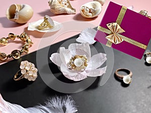 White pearl gold jewelry and gift box with pink roses petal seashell  still life pink and black background