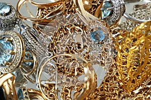 Jewerly scrap of gold and silver, many chains, rings, earrings on silver background, pawnshop concept