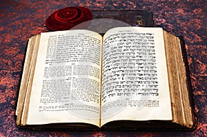 Jewish Bible. An open old Jewish book and a red knitted jewish bale. Torah in Hebrew and Aramaic. Closeup of Hebrew text