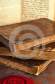 Jewish Bible. A stack of old leather-bound Jewish books with gold stamping, an open book and red knitted jewish bale