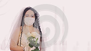 A Jewish bride in a wedding dress and a veil in a medical mask looks at the camera with smiling eyes