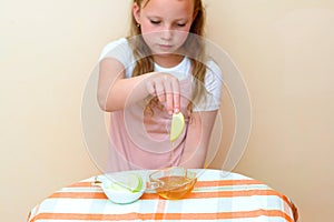 Jewish child dipping apple slices into honey on Rosh HaShanah.