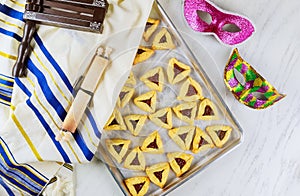 Jewish cookies Haman ears in baking pan for Purim with mask, tallit and noisemaker