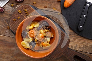 Jewish cuisine dish sweet tsimes with carrot dates in a clay plate on a wooden board. photo