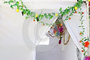 Jewish festival of Sukkot. Traditional succah (hut) from white fabric and colorful decorations photo