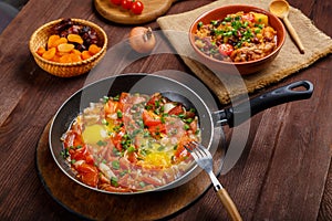 Jewish food hot cholent and shakshuka in a frying pan on a set Shabbat table.