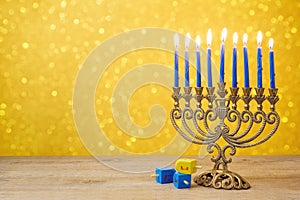 Jewish Hanukkah background with vintage menorah and spinning top dreidel over lights bokeh photo