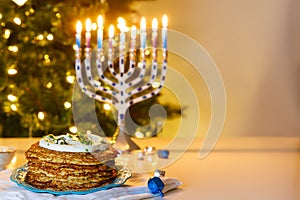 Jewish holiday dinner with Hanukkah menorah and potato latkes.