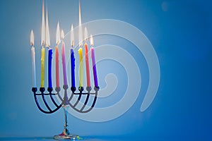 Jewish holiday Hanukkah background with menorah traditional candelabra and burning colorful candles.