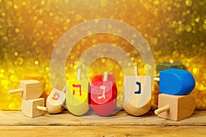 Jewish holiday Hanukkah background with spinning top dreidel on wooden table over golden bokeh