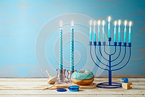 Jewish holiday Hanukkah concept with menorah, candles and traditional donut on wooden table. Background for greeting card or