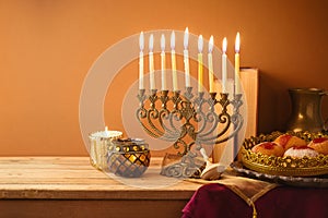 Jewish holiday Hanukkah concept with vintage menorah, sufganiyah and books on wooden table