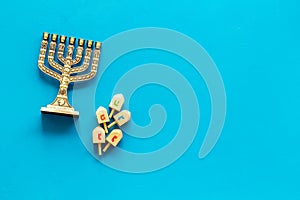 Jewish holiday Hanukkah with menorah - traditional Candelabra - and wooden dreidels spinning top. Blue background, top