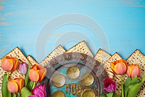 Jewish holiday Passover celebration concept with seder plate, matzah and tulip flowers on wooden table. Pesach background