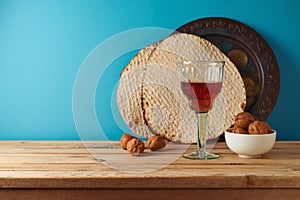 Jewish holiday Passover concept with wine glass, matzah and seder plate on wooden table