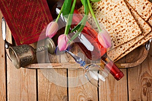Jewish holiday Passover Pesah celebration with matzoh, tulip flowers and wine bottle on wooden background.