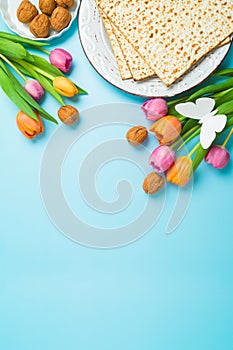 Jewish holiday Passover vertical greeting card with matzah and spring tulip flowers on blue background.