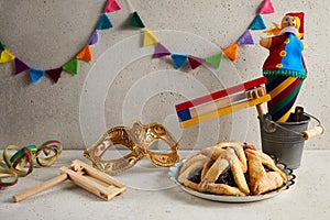 Jewish holiday Purim background with hamantaschen or hamans ears cookies, carnival mask and noisemaker