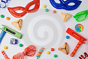 Jewish holiday Purim concept with hamantaschen cookies, carnival mask and noisemaker on white background.