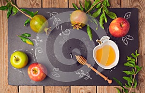 Jewish holiday Rosh Hashana background with apples, pomegranate and honey on blackboard. View from above.