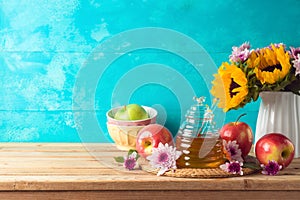 Jewish holiday Rosh Hashana background with honey jar, apple and sunflowers on wooden table