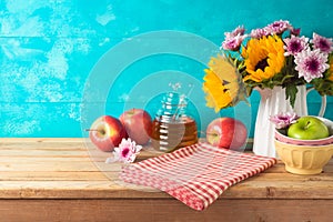 Jewish holiday Rosh Hashana background with honey jar, apples and sunflowers on wooden table. Kitchen counter with tablecloth and