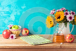 Jewish holiday Rosh Hashana background with honey jar, apples and sunflowers on wooden table. Kitchen counter with tablecloth and