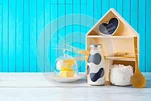 Jewish holiday Shavuot background with toy house, milk bottle and cottage cheese on wooden table