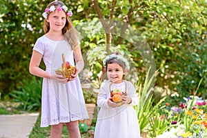 Jewish Holiday Shavuot.Harvest.Two little girls in white dress holds a basket with fresh fruit in a summer garden.