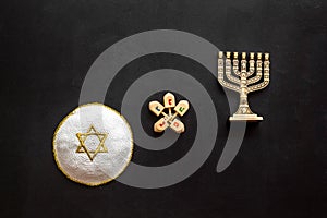 Jewish Kippah Yarmulkes hats with menorah on black wooden table. Top view