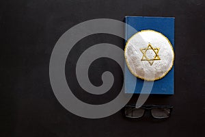 Jewish Kippah Yarmulkes hats with Star of David on Prayer book. Religion Judaisim symbols on black table. Top view photo