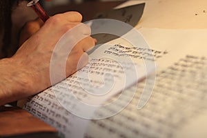 Jewish man with beard writing on a parchment scroll. Photo taken on: December 30th,2015