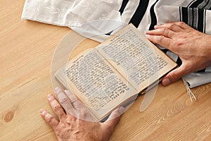 Jewish man hands holding a Prayer book, praying, next to tallit. Jewish traditional symbols. Rosh hashanah jewish New Year holida