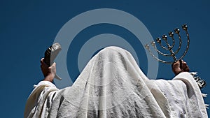 Jewish man holding Jewish symbols prying outdoors