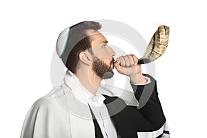 Jewish man with kippah and tallit blowing shofar on white background. Rosh Hashanah celebration