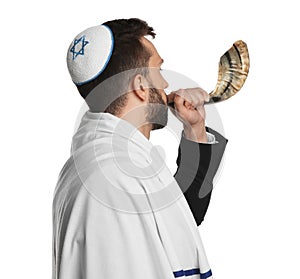 Jewish man with kippah and tallit blowing shofar on white background. Rosh Hashanah celebration