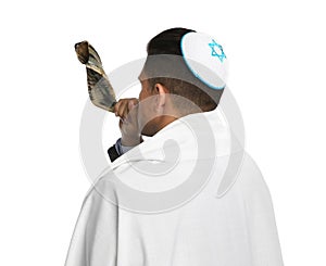 Jewish man with kippah and tallit blowing shofar on white. Rosh Hashanah celebration