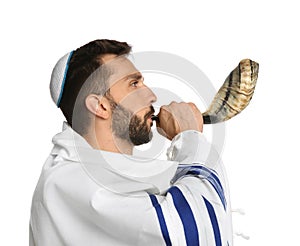Jewish man with kippah and tallit blowing shofar on white. Rosh Hashanah celebration