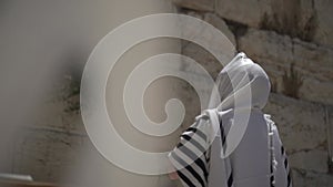 Jewish man pray alone at the wailing wall, Cotel. Strength his believe and faith to god wearing a Tallit and Tefillin