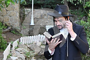 Jewish man reading outdoors with a chain loupe