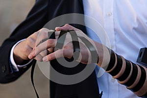 Jewish man wrapping tefillin around his left arm and hand