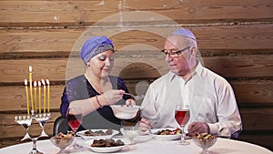 Jewish married couple a wife in a headdress a man in a kippah at the table during the days of Hanukkah dines.