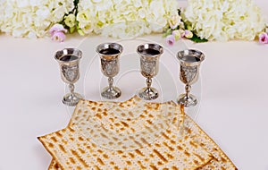 Jewish matzah bread on white background with four wine cups. Passover holiday concept