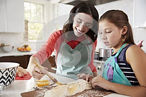 Jewish mother and daughter glazing dough for challah bread