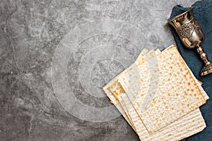 Jewish Passover holiday. Matza and glass for wine on a grey background. Top view. With copy space