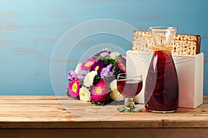 Jewish Passover holiday Pesah celebration concept with matzoh, wine and flowers over blue retro background