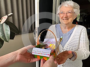 Jewish person giving Mishloach manot Purim basket gift of food to active senior Jewish woman Purim day