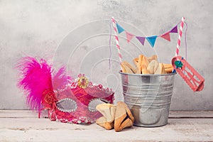 Jewish Purim holiday concept with hamantaschen cookies or hamans ears in bucket and carnival mask