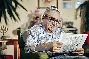 Jewish senior with glasses in the armchair reading a torah book